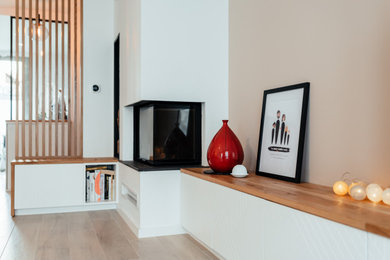 Imagen de salón abierto actual grande con paredes beige, suelo de madera clara, chimenea de esquina, televisor independiente y suelo beige