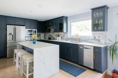Eat-in kitchen - large transitional l-shaped light wood floor and beige floor eat-in kitchen idea in Boston with an undermount sink, shaker cabinets, blue cabinets, quartz countertops, white backsplash, porcelain backsplash, stainless steel appliances, an island and white countertops