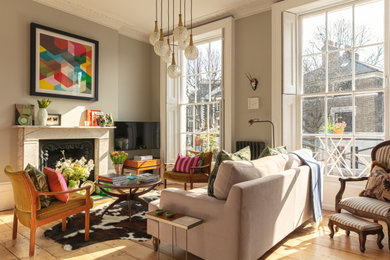 Пример оригинального дизайна: гостиная комната среднего размера в стиле фьюжн с серыми стенами, паркетным полом среднего тона, стандартным камином, фасадом камина из камня, телевизором на стене и коричневым полом