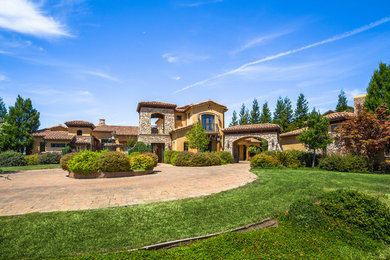 Huge tuscan beige split-level stone exterior home photo in Orange County