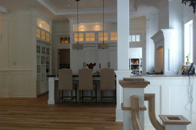 Example of a large classic u-shaped medium tone wood floor and multicolored floor kitchen design in Ottawa with an undermount sink, shaker cabinets, white cabinets, granite countertops, white backsplash, paneled appliances and an island