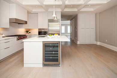 Inspiration for a transitional l-shaped light wood floor and beige floor open concept kitchen remodel in Toronto with an undermount sink, flat-panel cabinets, white cabinets, white backsplash, stainless steel appliances, an island and white countertops