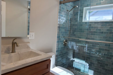Mid-sized trendy beige tile and porcelain tile porcelain tile, gray floor and single-sink bathroom photo in Boston with shaker cabinets, medium tone wood cabinets, a one-piece toilet, beige walls, an integrated sink, solid surface countertops, beige countertops, a niche and a built-in vanity