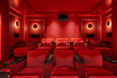 Large trendy enclosed carpeted and red floor home theater photo in Dublin with red walls and a projector screen