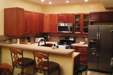 Example of an u-shaped ceramic tile eat-in kitchen design in Other with a drop-in sink, raised-panel cabinets, light wood cabinets, laminate countertops, beige backsplash, ceramic backsplash and stainless steel appliances