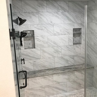 Exemple d'une grande salle de bain principale chic avec un placard avec porte à panneau surélevé, des portes de placard en bois brun, un espace douche bain, des carreaux de porcelaine, un mur gris, sol en stratifié, un lavabo encastré, un plan de toilette en granite, un sol marron, une cabine de douche à porte battante et un plan de toilette gris.