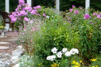 This is an example of a mid-sized traditional partial sun backyard stone landscaping in New York.