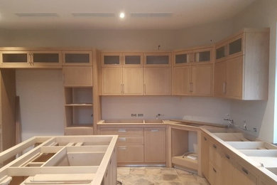 This is an example of a large u-shaped separate kitchen in Saint Petersburg with with island and brown benchtop.