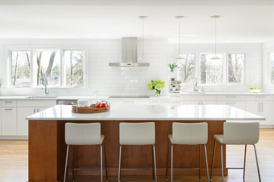 Kitchen - contemporary galley light wood floor and beige floor kitchen idea in Boston with white backsplash, stainless steel appliances, an island, an undermount sink, flat-panel cabinets, white cabinets, subway tile backsplash and white countertops