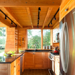 Удачное сочетание для дизайна помещения: маленькая кухня в стиле рустика с столешницей из гранита, техникой из нержавеющей стали, серым полом, врезной раковиной, фасадами цвета дерева среднего тона, фартуком с окном, полуостровом и полом из сланца - самое интересное для вас