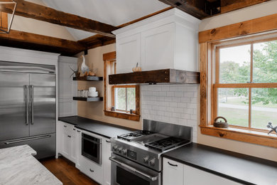 Eat-in kitchen - farmhouse galley eat-in kitchen idea in Boston with a farmhouse sink, white cabinets, quartzite countertops, subway tile backsplash, stainless steel appliances and an island