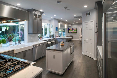 Inspiration for a mid-sized contemporary u-shaped kitchen in Los Angeles with grey cabinets, multi-coloured splashback, mosaic tile splashback, stainless steel appliances, medium hardwood floors, with island, brown floor, white benchtop, a farmhouse sink, raised-panel cabinets and marble benchtops.