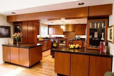 This is an example of a mid-sized contemporary u-shaped eat-in kitchen in Boise with a double-bowl sink, flat-panel cabinets, dark wood cabinets, granite benchtops, stainless steel appliances, light hardwood floors, with island and brown floor.