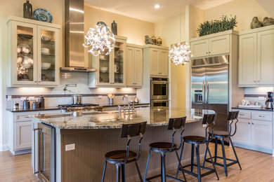 Inspiration for a large timeless l-shaped medium tone wood floor open concept kitchen remodel in Austin with an undermount sink, flat-panel cabinets, white cabinets, granite countertops, white backsplash, subway tile backsplash, stainless steel appliances and an island