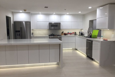 Photo of a large modern l-shaped eat-in kitchen in Miami with a single-bowl sink, flat-panel cabinets, white cabinets, quartz benchtops, white splashback, stainless steel appliances, porcelain floors, with island, beige floor and white benchtop.