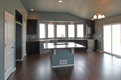 Example of a large minimalist single-wall medium tone wood floor, brown floor and vaulted ceiling kitchen pantry design in Denver with shaker cabinets, dark wood cabinets and an island