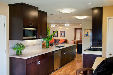 Kitchen - mid-sized contemporary galley medium tone wood floor kitchen idea in San Francisco with an undermount sink, flat-panel cabinets, dark wood cabinets, marble countertops, white backsplash, glass tile backsplash and stainless steel appliances