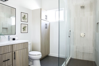 Example of a mid-sized beach style master white tile and porcelain tile porcelain tile and gray floor corner shower design in Los Angeles with flat-panel cabinets, gray cabinets, white walls, an undermount sink, quartz countertops, a hinged shower door and white countertops