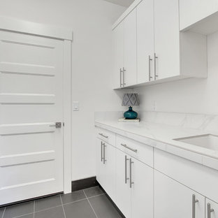 Photo of a medium sized contemporary galley separated utility room in Portland with a built-in sink, flat-panel cabinets, white cabinets, tile countertops and white walls.