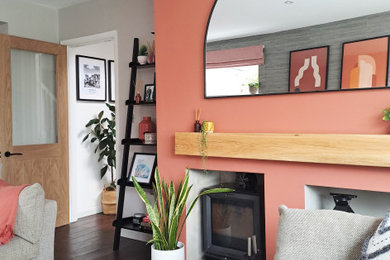 Inspiration pour un petit salon gris et rose design ouvert avec un mur gris, un poêle à bois, un manteau de cheminée en plâtre et un sol marron.