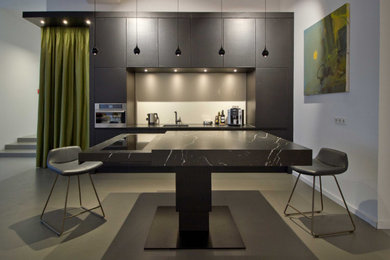 Einzeilige, Große Moderne Wohnküche mit Unterbauwaschbecken, flächenbündigen Schrankfronten, schwarzen Schränken, Marmor-Arbeitsplatte, Küchenrückwand in Metallic, Rückwand aus Spiegelfliesen, schwarzen Elektrogeräten, Betonboden, Kücheninsel, grauem Boden und schwarzer Arbeitsplatte in Frankfurt am Main