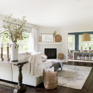 Inredning av ett modernt stort allrum med öppen planlösning, med beige väggar, mörkt trägolv, en öppen hörnspis, en spiselkrans i tegelsten och brunt golv