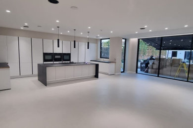 This is an example of a large galley open plan kitchen in Essex with white cabinets, an island and black worktops.