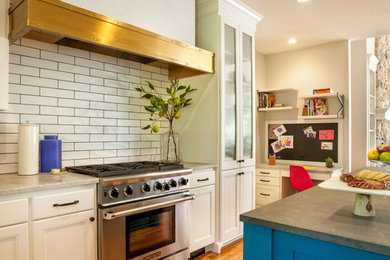 Example of a large transitional u-shaped medium tone wood floor eat-in kitchen design in Portland with a farmhouse sink, glass-front cabinets, white cabinets, marble countertops, white backsplash, subway tile backsplash, stainless steel appliances and an island