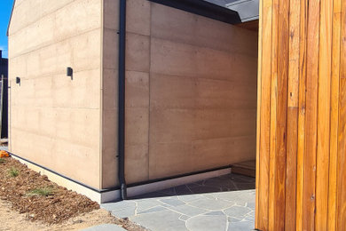 Modelo de distribuidor abovedado costero de tamaño medio con paredes beige, suelo de madera en tonos medios, puerta pivotante, puerta de madera clara y suelo beige