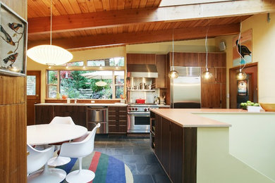 Mid-sized modern eat-in kitchen in Seattle with stainless steel appliances, an undermount sink, flat-panel cabinets, dark wood cabinets, slate floors and black floor.