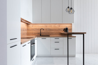 Example of a mid-sized minimalist l-shaped porcelain tile and white floor open concept kitchen design in Sydney with white cabinets, wood countertops, wood backsplash, an island, brown countertops, a single-bowl sink, flat-panel cabinets, brown backsplash and black appliances