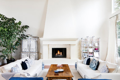 Large beach style formal and open concept medium tone wood floor living room photo in Los Angeles with white walls, a standard fireplace, a stone fireplace and no tv