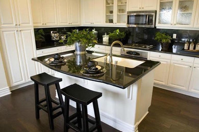Inspiration for a mid-sized timeless l-shaped dark wood floor eat-in kitchen remodel in Other with a double-bowl sink, raised-panel cabinets, white cabinets, granite countertops, black backsplash, stone slab backsplash, stainless steel appliances and an island