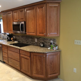 Design ideas for a mid-sized traditional u-shaped kitchen pantry in Boston with raised-panel cabinets, medium wood cabinets, granite benchtops, brown splashback, stainless steel appliances, terrazzo floors and a peninsula.