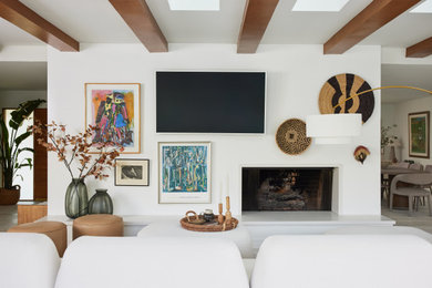 ロサンゼルスにある高級な広いミッドセンチュリースタイルのおしゃれなオープンリビング (白い壁、淡色無垢フローリング、標準型暖炉、壁掛け型テレビ、ベージュの床、表し梁) の写真