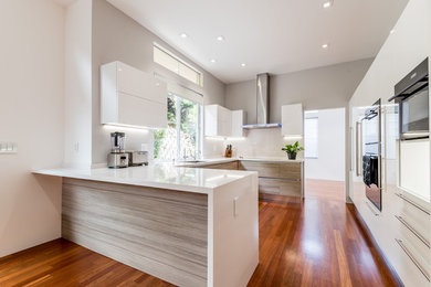 Design ideas for a mid-sized modern u-shaped eat-in kitchen in San Francisco with an undermount sink, flat-panel cabinets, medium wood cabinets, quartz benchtops, stainless steel appliances, dark hardwood floors, a peninsula and brown floor.