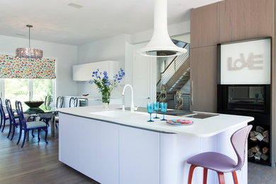 Large eclectic galley medium tone wood floor and brown floor eat-in kitchen photo in New York with an undermount sink, flat-panel cabinets, light wood cabinets, solid surface countertops, white appliances and an island