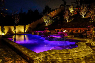 Design ideas for a mid-sized country custom-shaped pool in Orange County with concrete pavers.