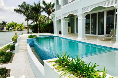 Example of a large beach style backyard tile and rectangular infinity hot tub design in Other