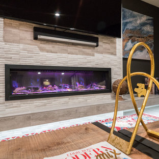 Photo of a medium sized classic look-out basement in Other with black walls, carpet, a ribbon fireplace, a tiled fireplace surround and brown floors.