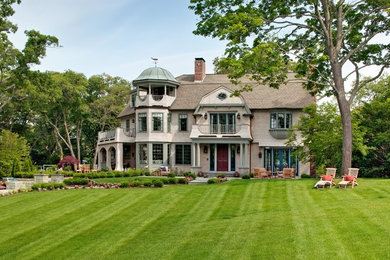 Large ornate beige three-story wood house exterior photo in Boston with a gambrel roof