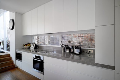 Design ideas for a mid-sized modern galley eat-in kitchen in Sydney with an undermount sink, flat-panel cabinets, white cabinets, quartz benchtops, grey splashback, stone slab splashback, stainless steel appliances, light hardwood floors and with island.