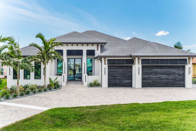 Large danish white one-story stucco house exterior photo in Tampa with a hip roof, a tile roof and a gray roof