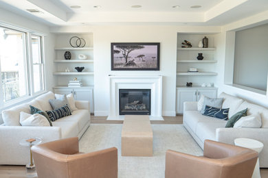 Example of a large 1960s formal and open concept light wood floor and beige floor living room design with white walls, a standard fireplace, a stone fireplace and a wall-mounted tv