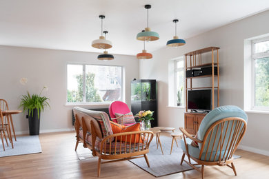 Example of a large 1950s open concept medium tone wood floor living room design in Gloucestershire with gray walls