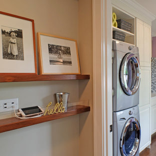 Small classic single-wall utility room in Chicago with white cabinets, purple walls, medium hardwood flooring, a stacked washer and dryer, raised-panel cabinets and engineered stone countertops.