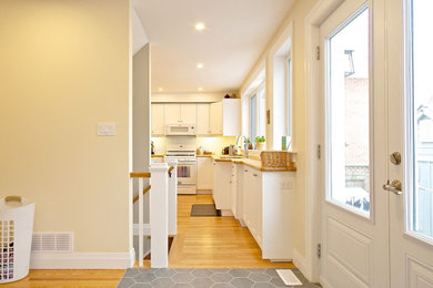 Inspiration for a mid-sized craftsman l-shaped medium tone wood floor and brown floor eat-in kitchen remodel in Other with a double-bowl sink, shaker cabinets, white cabinets, wood countertops, white appliances, an island and brown countertops