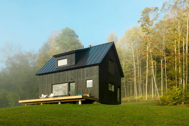 Photo of a small scandinavian two-storey black house exterior in Burlington with wood siding, a gable roof and a metal roof.