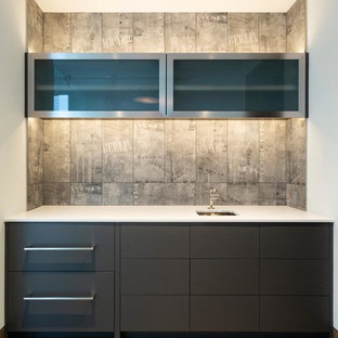 デンバーの中サイズのモダンスタイルのおしゃれなウェットバー (アンダーカウンターシンク、フラットパネル扉のキャビネット、黒いキャビネット、クオーツストーンカウンター、グレーのキッチンパネル、セメントタイルのキッチンパネル、無垢フローリング、茶色い床、白いキッチンカウンター) の写真