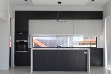 Photo of a modern kitchen in Canberra - Queanbeyan with an undermount sink, marble benchtops, glass sheet splashback, grey floor and black benchtop.